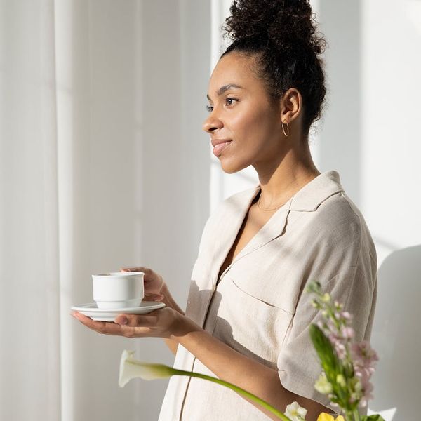 Person drinking tea and looking out a window after a morning exercise session.