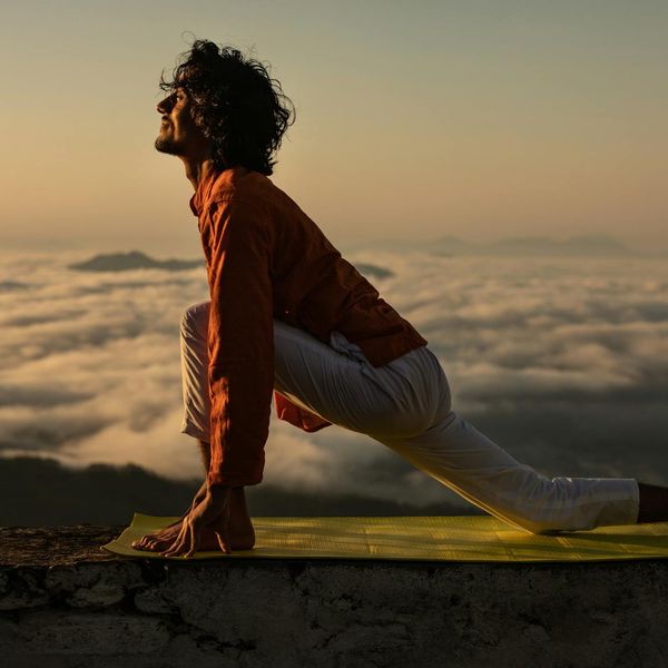 Silhouette of a person doing a yoga pose against a sunrise.